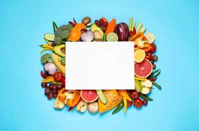 Flat lay composition with fresh organic vegetables, fruits and blank card on light blue background. Space for text