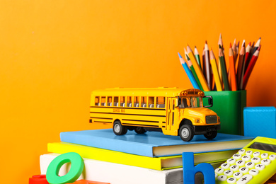 School bus model and stationery on orange background. Transport for students