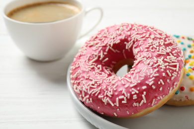 Photo of Yummy donuts with sprinkles on white wooden table, closeup