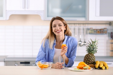 Woman making orange juice at table in kitchen. Healthy diet