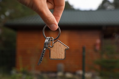 Photo of Woman holding house keys outdoors, closeup. Real estate agent
