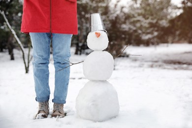 Young woman near snowman outdoors on winter day, closeup. Space for text