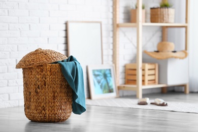 Wicker basket with blanket in modern room interior. Space for text