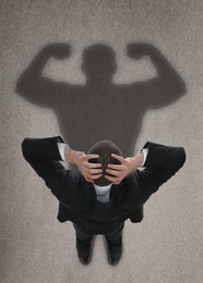Businessman and shadow of strong muscular man on floor in front of him. Concept of inner strength