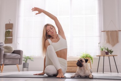 Beautiful woman with dog practicing yoga at home