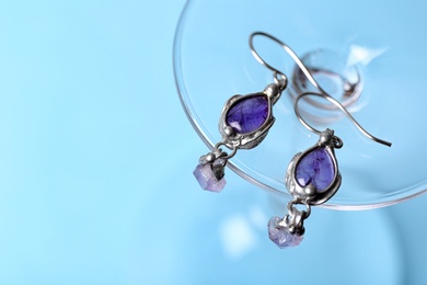 Beautiful pair of silver earrings with amethyst gemstones on light blue background