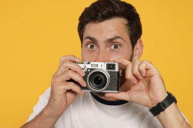 Photo of Man with camera taking photo on yellow background. Interesting hobby