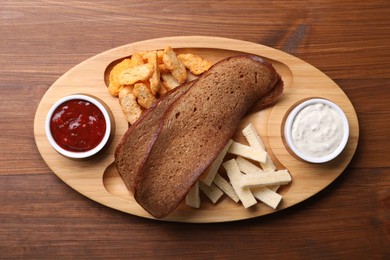 Tray with different crispy rusks and dip sauces on wooden table, top view
