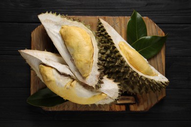Pieces of fresh ripe durian on black wooden table, top view
