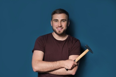 Young working man with hammer on color background