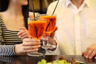 Lovely couple with Aperol spritz cocktails resting together at restaurant, closeup