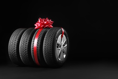 Gift set of wheels with winter tires on black background, space for text