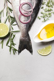 Flat lay composition with fresh raw dorado fish and ingredients on light grey table, space for text