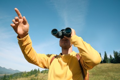 Photo of Man with binoculars in mountains on sunny day