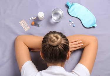 Woman surrounded by different pills on bedsheet, top view. Insomnia treatment