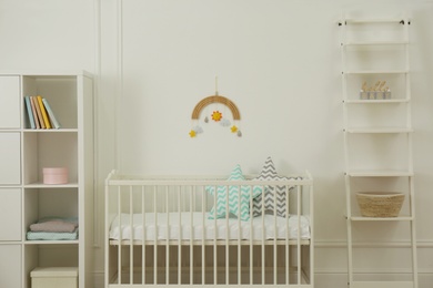 Cute baby room interior with stylish furniture and pillows