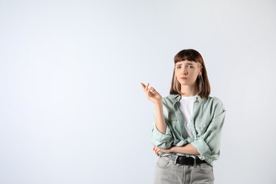 Photo of Portrait of confused young girl on white background. Space for text