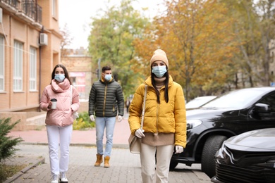 People in medical face masks walking outdoors. Personal protection during COVID-19 pandemic