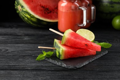 Slate board with juicy watermelon and lime on black wooden table, space for text