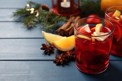 Delicious punch drink with cranberries and orange on blue wooden table. Space for text