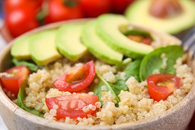 Photo of Delicious quinoa salad with tomatoes, avocado slices and spinach leaves, closeup