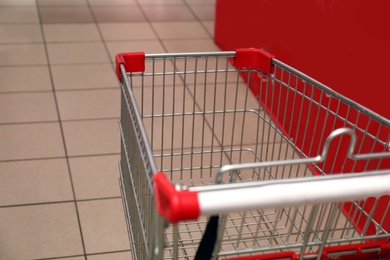 Empty metal shopping cart in supermarket, closeup
