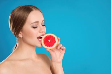 Photo of Young woman with cut grapefruit on blue background, space for text. Vitamin rich food