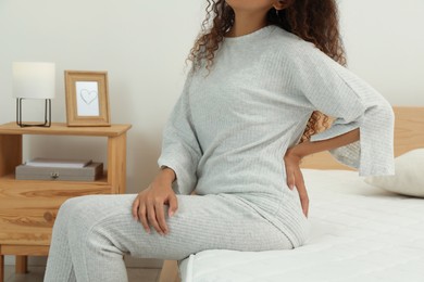 Woman suffering from back pain after sleeping on uncomfortable mattress at home, closeup