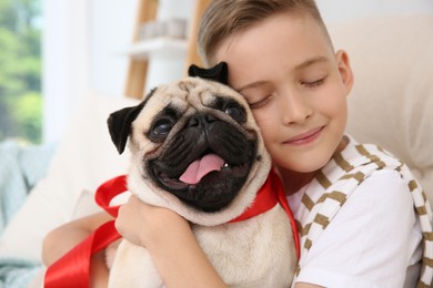 Photo of Little boy with cute pug dog at home