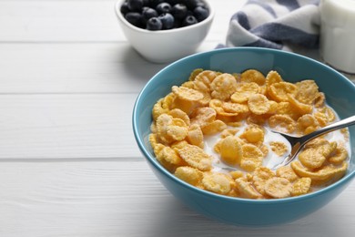 Bowl of tasty corn flakes served on white wooden table. Space for text