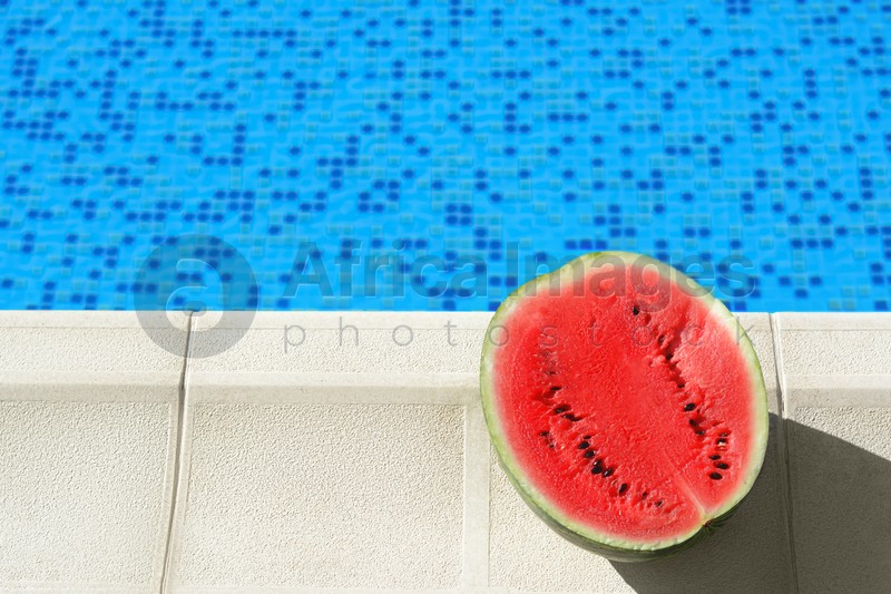 Half of fresh juicy watermelon near swimming pool outdoors. Space for text