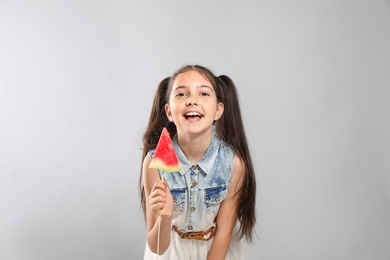 Cute little girl with watermelon on grey background