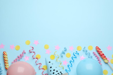 Flat lay composition with serpentine streamers and party accessories on light blue background, space for text. Birthday surprise