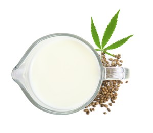Glass jug with fresh hemp milk, seeds and leaf on white background, top view