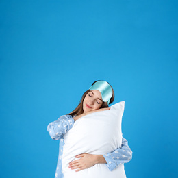 Beautiful woman with pillow on light blue background. Bedtime