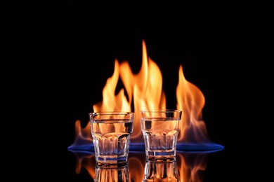 Vodka in glasses and flame on black background