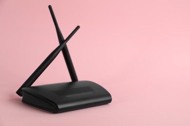 Modern Wi-Fi router on light pink background. Space for text