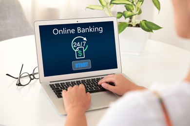 Woman using online banking application via laptop at table, closeup