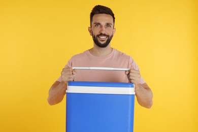 Happy man with cool box on yellow background