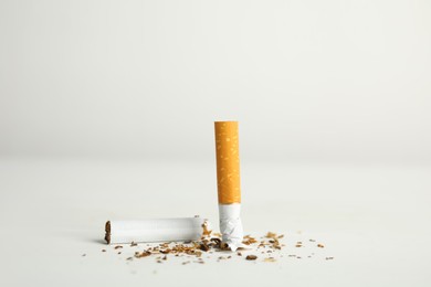 Photo of Broken cigarette on white table. Quitting smoking concept
