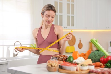 Woman with measuring tape and different products in kitchen. Keto diet
