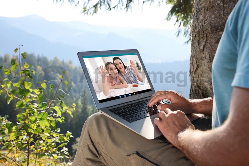 Man talking with his wife and daughter via videocall application outdoors, closeup