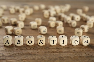 Word Abortion made of cubes on wooden table, closeup