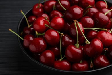 Photo of Bowl with ripe sweet cherries on dark wooden table, closeup