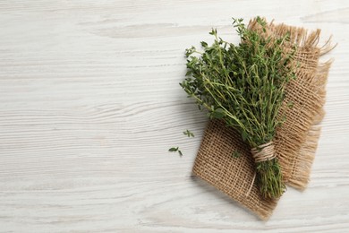 Bunch of aromatic thyme on white wooden table, top view. Space for text