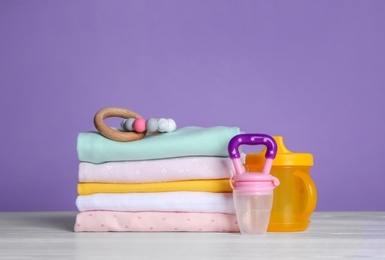 Children's accessories and stack of clothes on white wooden table