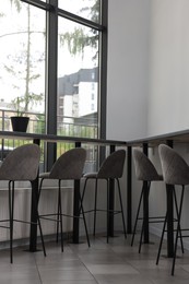 Table and bar stools near window in hostel dining room