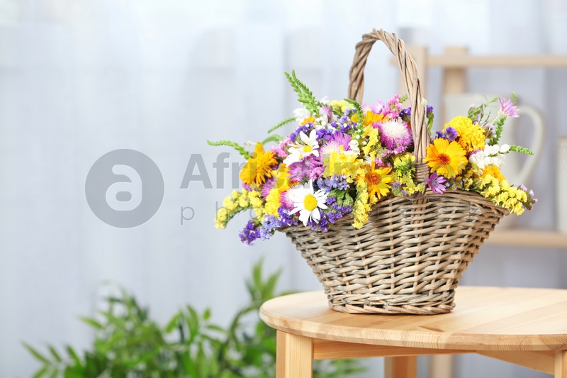 Photo of Wicker basket with beautiful wild flowers on table indoors