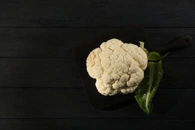 Photo of Fresh raw cauliflower on black wooden table, top view. Space for text