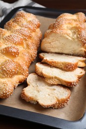 Baking tray with homemade braided bread on wooden table, closeup. Challah for Shabbat